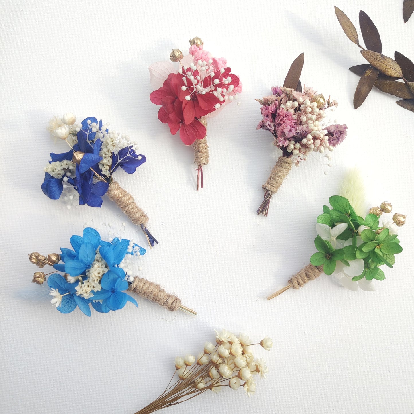 Collection de boutonnières artisanales en plusieurs couleurs, parfaites pour mariages.