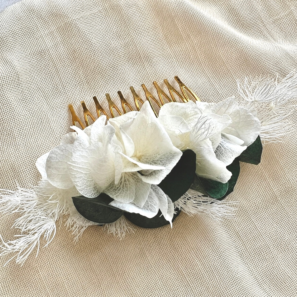 Peigne de mariage artisanal Clémence avec structure dorée et fleurs stabilisées.