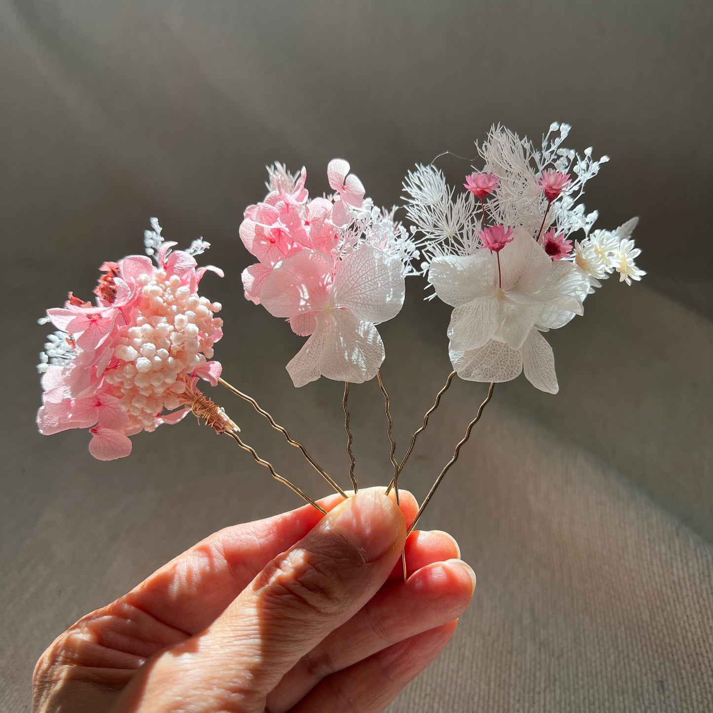 Rosée épingles en fleurs stabilisées roses et blanches tenues à la main