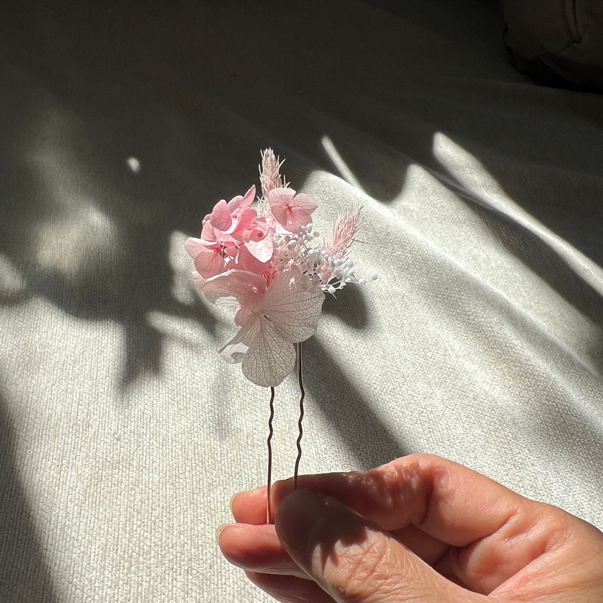 Épingles en fleurs stabilisées rose poudré et blanc présentées à la lumière naturelle