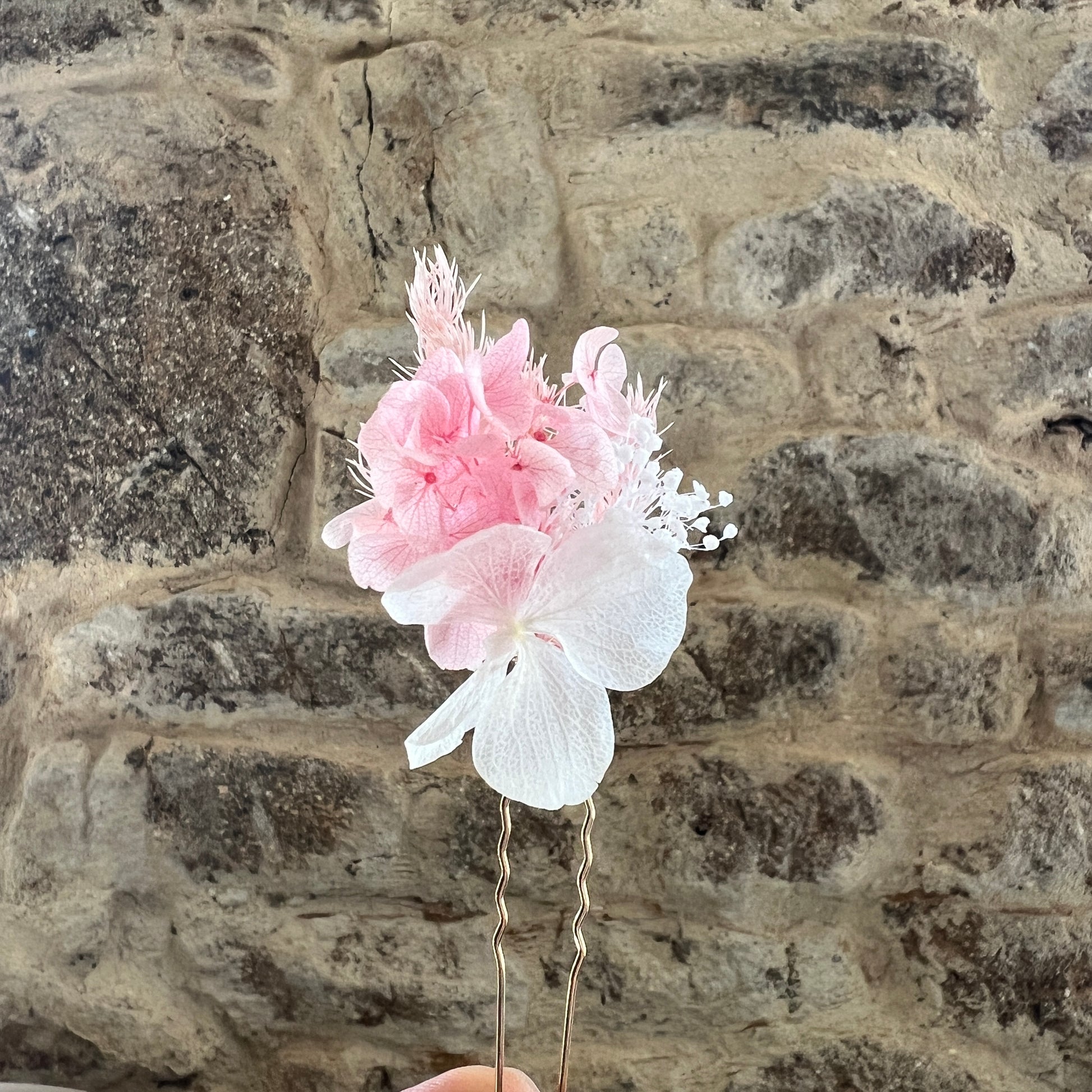 Épingles en fleurs stabilisées rose poudré et blanc présentées à la lumière naturelle