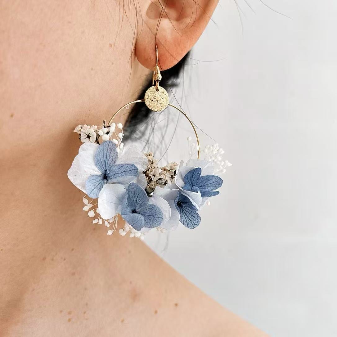 Boucles d’oreilles florales Azurine bleu ciel portées à l’oreille