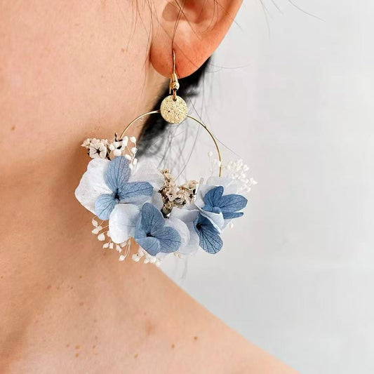 Boucles d’oreilles florales Azurine bleu ciel portées à l’oreille