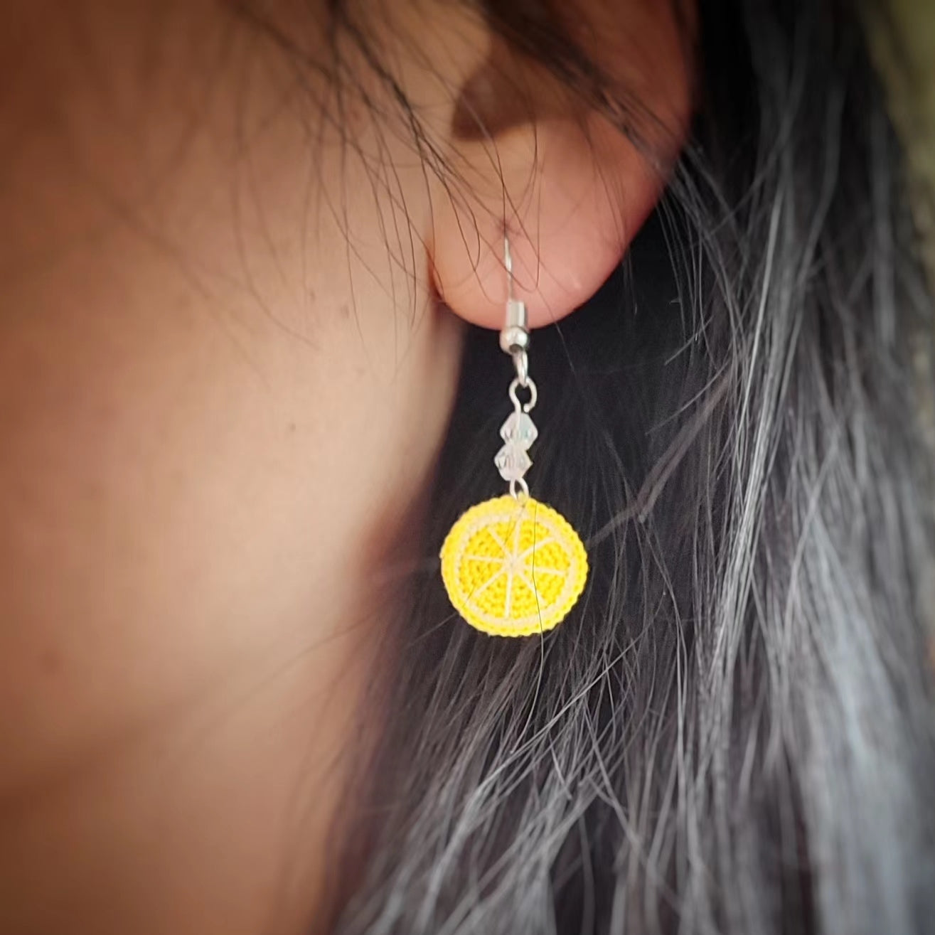 une boucle d'oreille en crochet fait main en forme de rondelle de citron jaune, parfaite pour apporter une touche de vitalité à votre style.