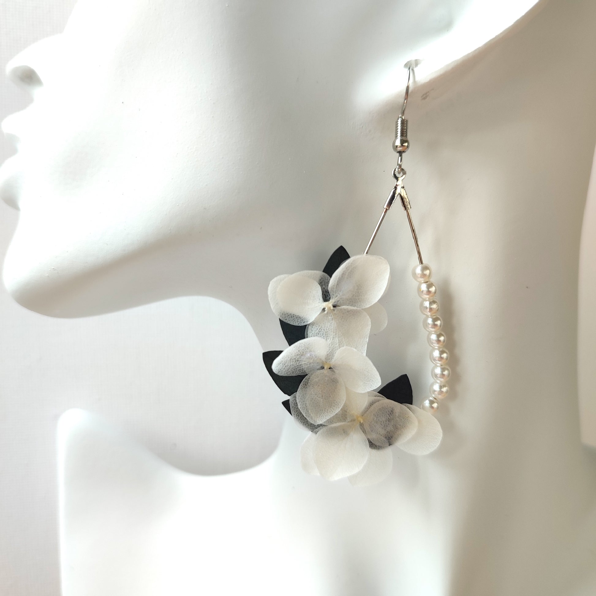 Image de boucles d'oreilles élégantes en perles et fleurs blanches stabilisées, faites à la main, parfaites pour les mariages et occasions spéciales