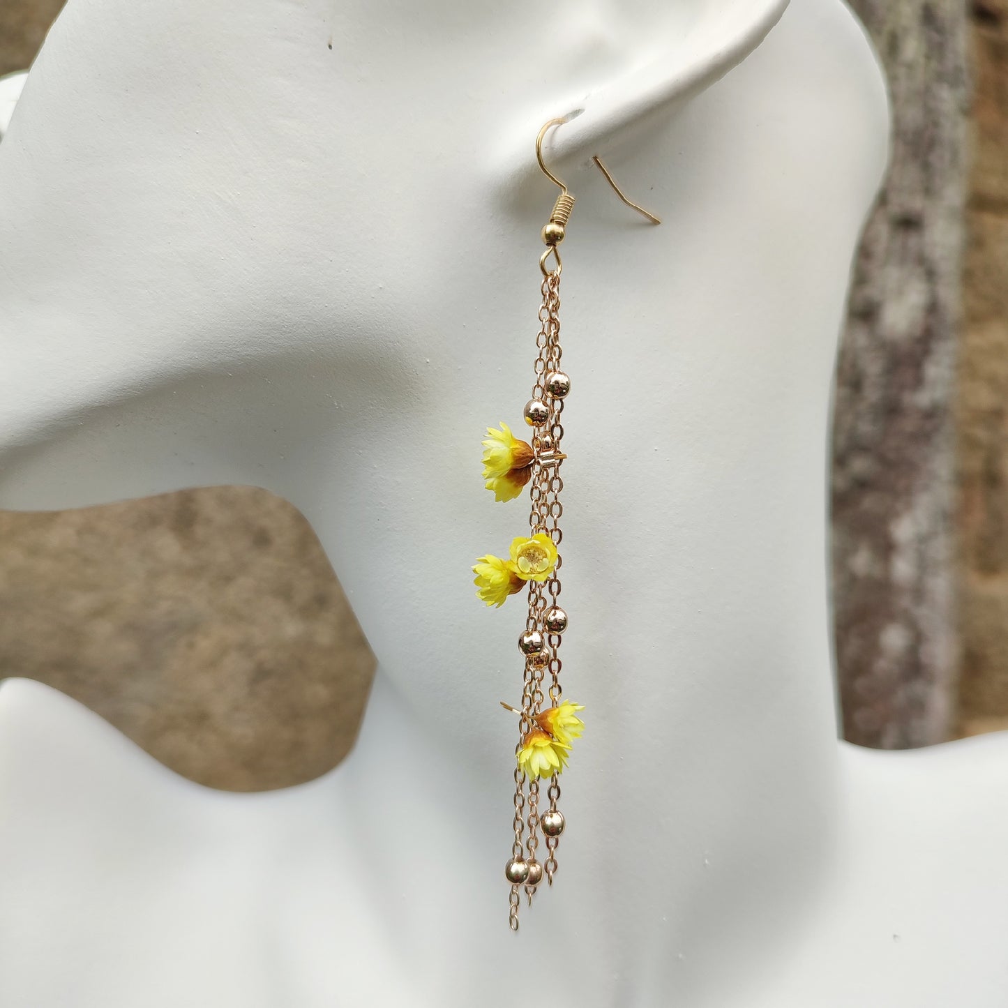 Élégantes boucles d’oreilles Élise avec fleurs séchées et chaînes dorées, inspirées de la nature pour un look unique.