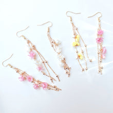 Charger l&#39;image dans la galerie, Boucles d’oreilles Élise en fleurs séchées, ornées de chaînes dorées et de perles délicates, disponibles en blanc, rose, et jaune.
