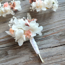 Charger l&#39;image dans la galerie, Boutonnière florale Clara avec des fleurs éternelles blanches et roses, posée sur un fond en bois naturel.
