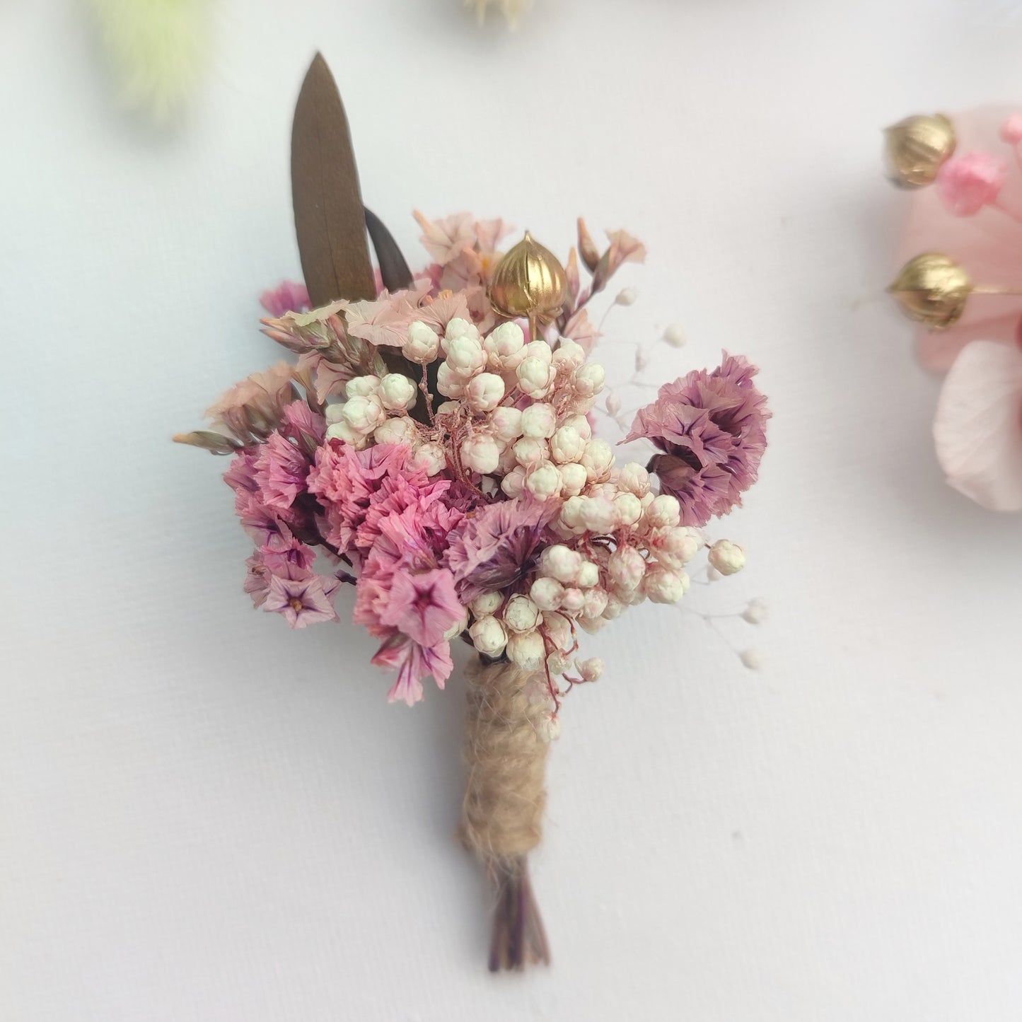 Boutonnière florale rose pastel avec des fleurs séchées et des feuilles marron.Boutonnière florale rose pastel avec des fleurs séchées et des feuilles marron.