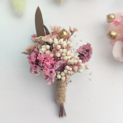 Boutonnière florale rose pastel avec des fleurs séchées et des feuilles marron.Boutonnière florale rose pastel avec des fleurs séchées et des feuilles marron.