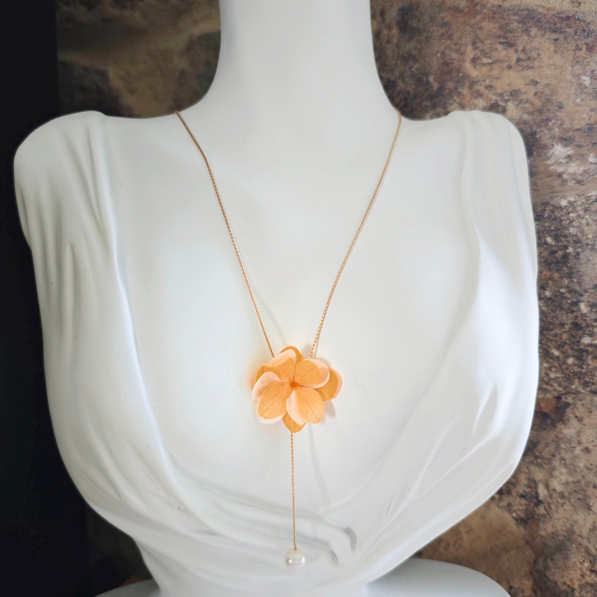 Collier artisanal avec fleur en tissu et perle nacrée, accessoire élégant pour cérémonie ou mariée.