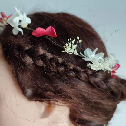 Couronne en fleurs stabilisées composée d'hortensias fuchsia et blancs, portée sur des cheveux bruns relevés en chignon.