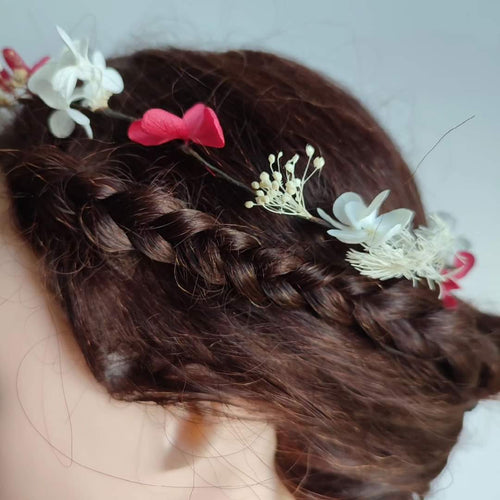 Couronne en fleurs stabilisées composée d'hortensias fuchsia et blancs, portée sur des cheveux bruns relevés en chignon.