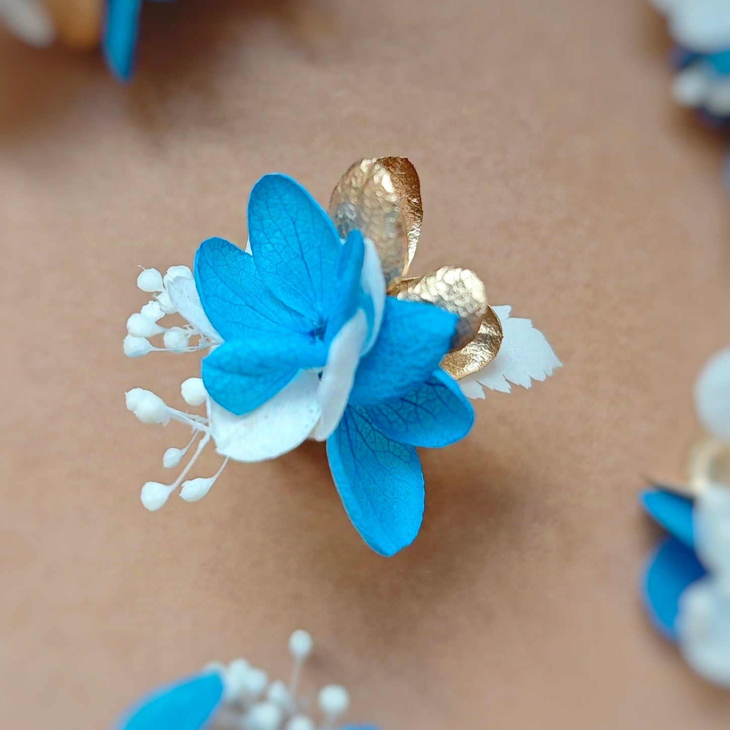 Détail de la bague en fleurs éternelles bleues, blanches et dorées, collection Léonie