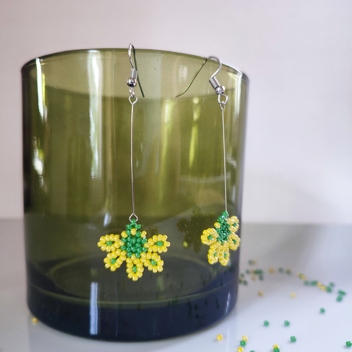 Élégantes boucles d'oreilles en perles jaunes avec une touche de vert.