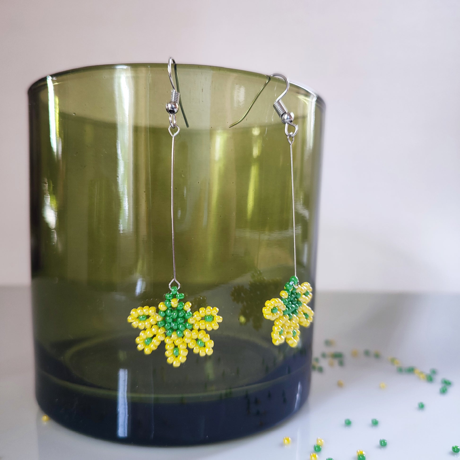 Élégantes boucles d'oreilles en perles jaunes avec une touche de vert.