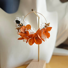 Charger l&#39;image dans la galerie, Boucle d’oreille en fleurs séchées orange et blanches portée sur un buste blanc, devant un mur en pierre naturelle.
