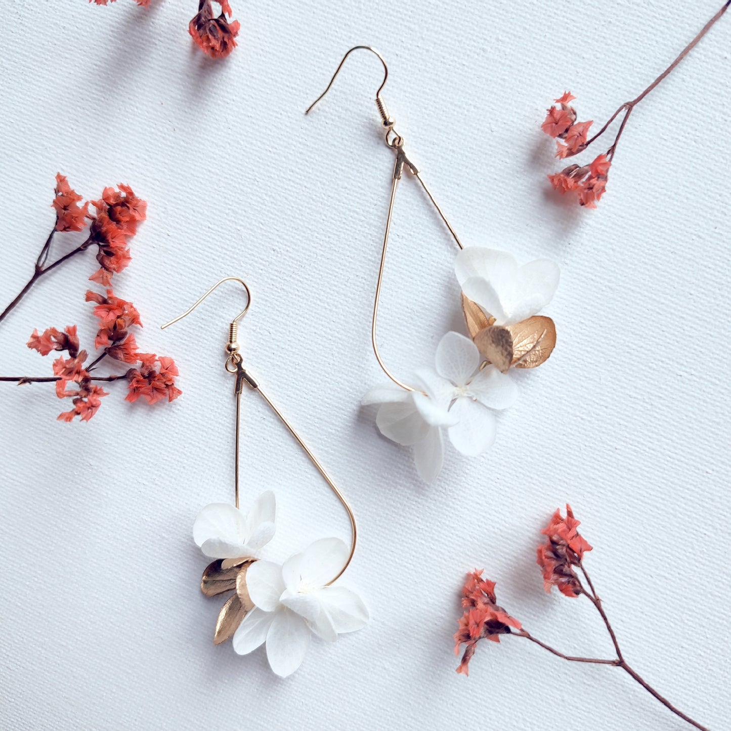 Gros plan de boucles d'oreilles en fleurs stabilisées blanches et dorées