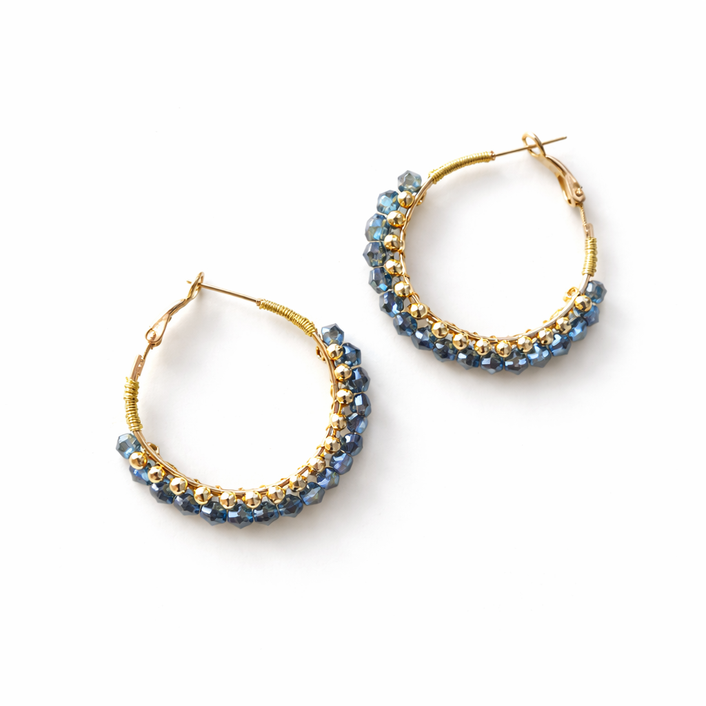 Créoles en perles facettées bleues et perles dorées sur fond blanc