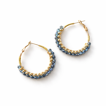 Créoles en perles facettées bleues et perles dorées sur fond blanc
