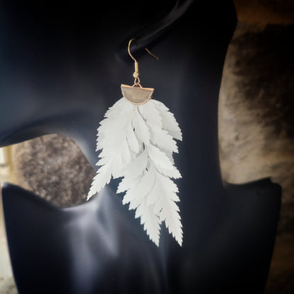 Vue rapprochée d'une boucle d'oreille en fougère stabilisées et séchées, mettant en valeur les détails des feuilles naturelles et le crochet en métal doré.