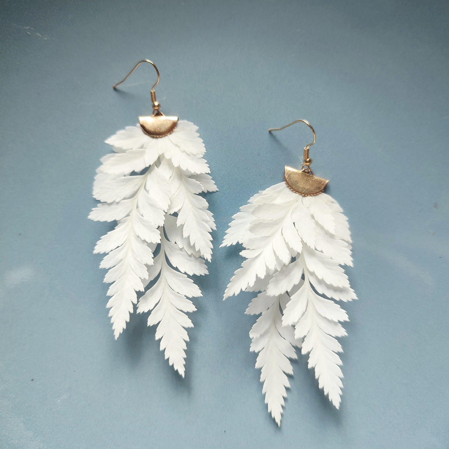 Boucles d'oreilles en fougère stabilisées et séchées, fabriquées à partir de feuilles naturelles, avec des attaches en métal doré.